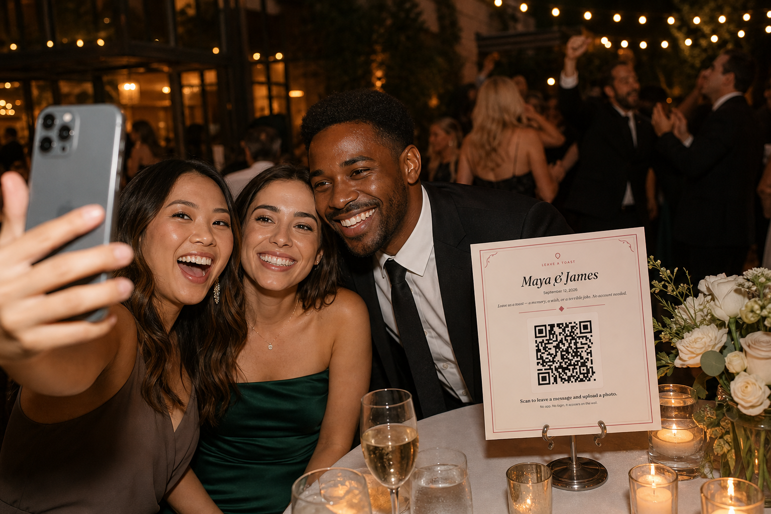 Guests take a selfie at a wedding reception with a Willow Book table sign and QR code visible on a nearby table